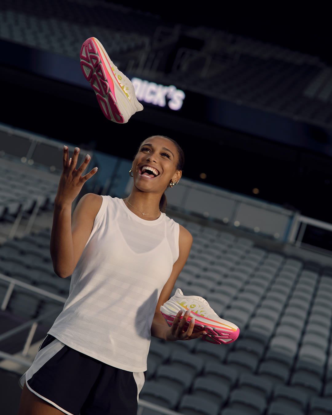 Anaiyah Robinson laughs while tossing a pair of running shoes in the air at the stadium.