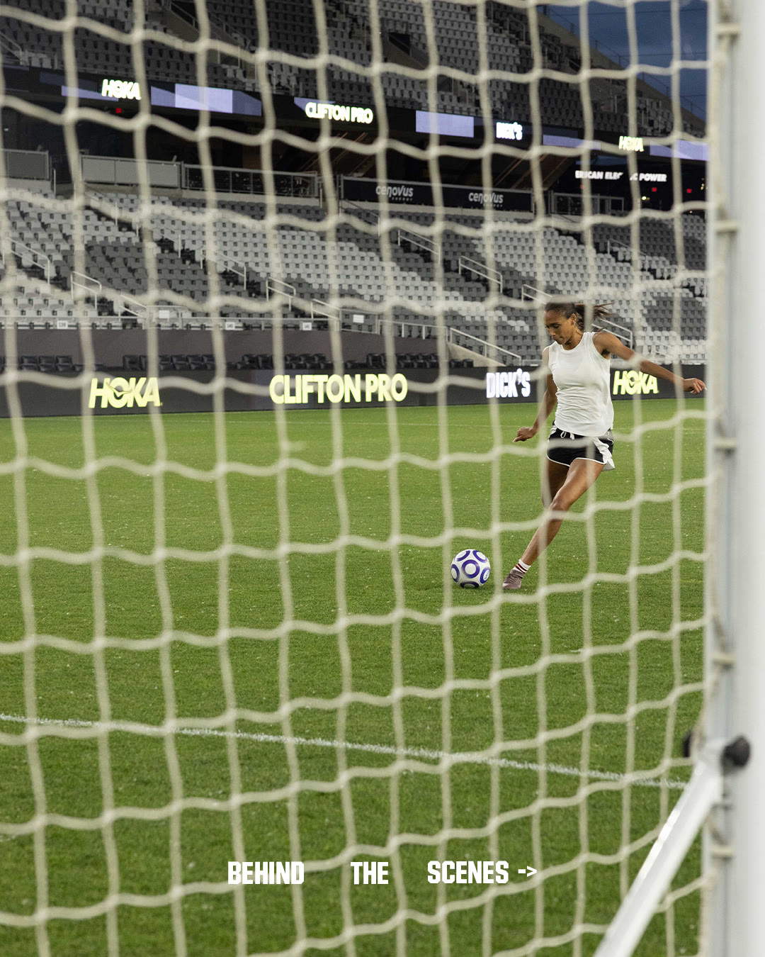 Anaiyah Robinson strikes a ball toward goal, seen through the net.