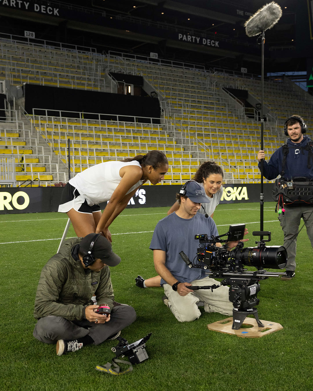 The film crew records Anaiyah Robinson stretching on the stadium field.