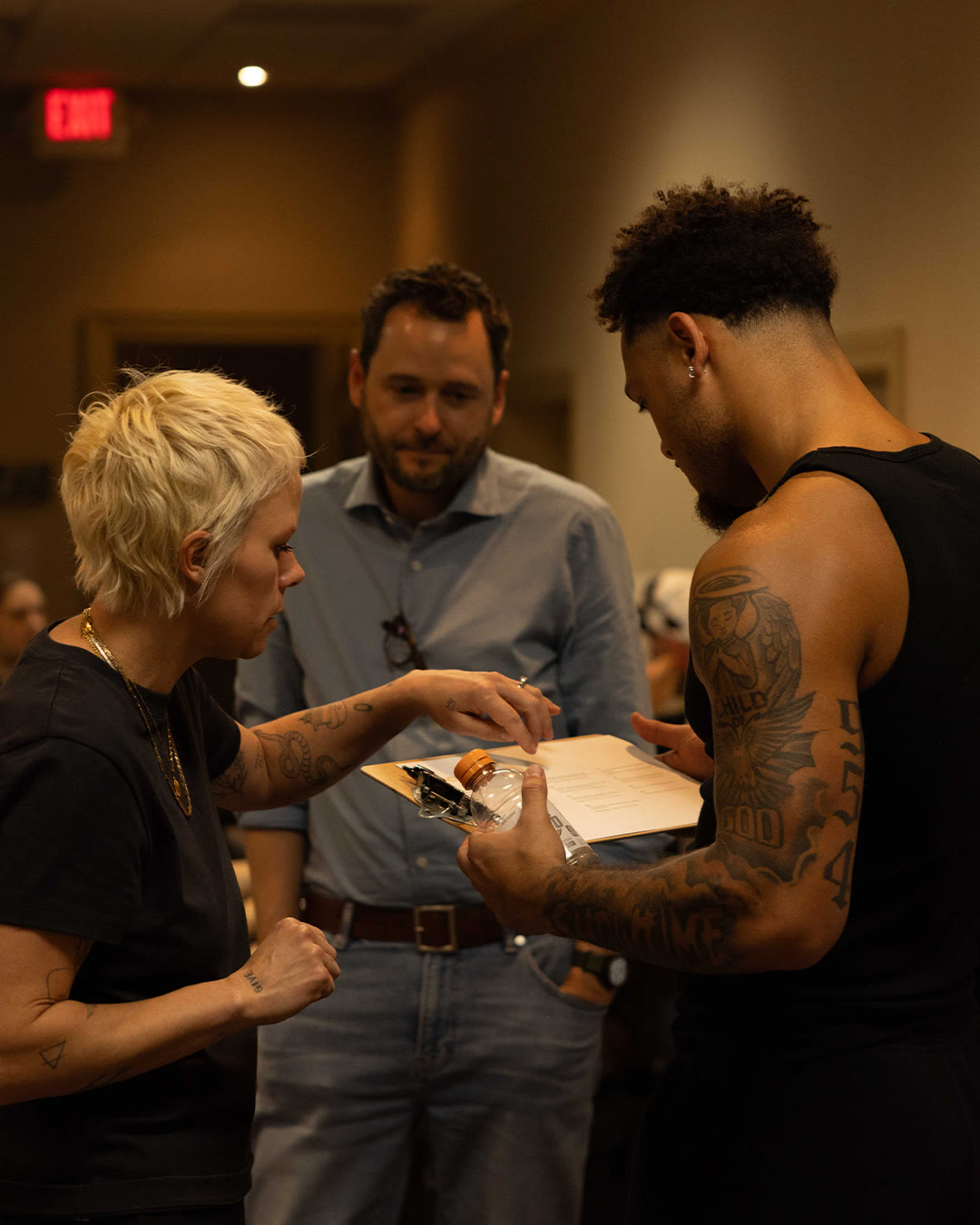 Brandon Inniss and two crew members review notes in a stadium hallway.